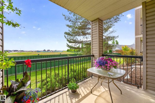Expansive covered balcony featuring a concrete floor, black metal railing, and neutral-toned siding - 133 2503 Hanna Crescent, Edmonton, AB 