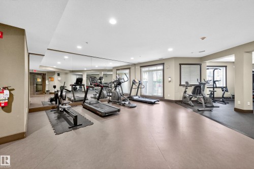 Fitness center with mirrored walls, multiple exercise machines, recessed lighting, and windows with blinds - 133 2503 Hanna Crescent, Edmonton, AB 