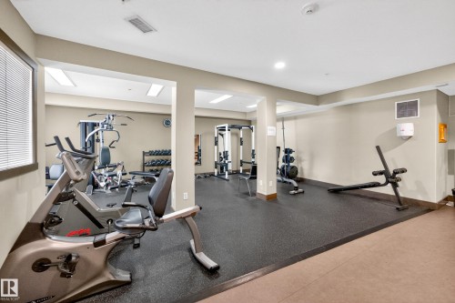 Dedicated fitness area featuring rubberized flooring, comprehensive exercise equipment, recessed lighting, and a large window with blinds - 133 2503 Hanna Crescent, Edmonton, AB 