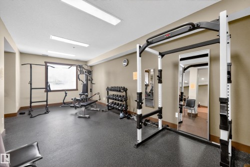 Dedicated fitness room featuring rubberized flooring, a large window, recessed lighting, and wall-mounted mirrors - 133 2503 Hanna Crescent, Edmonton, AB 