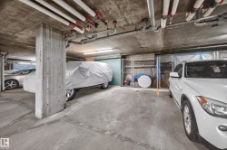 Concrete parking garage with exposed ceiling pipes and concrete support columns - 