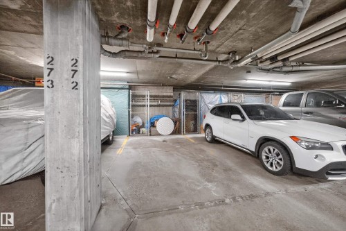 Concrete parking garage with designated parking spaces, overhead utility pipes, and exposed concrete ceiling - 133 2503 Hanna Crescent, Edmonton, AB 