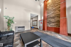 Spacious entry lobby featuring a stone accent wall, decorative wood columns, patterned tile flooring, and integrated wall lighting - 