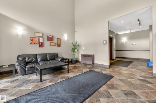 Lobby area featuring diamond-patterned floor tiling, wall sconces, and a high ceiling - 133 2503 Hanna Crescent, Edmonton, AB 