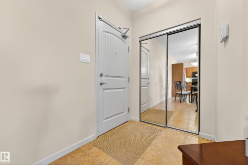 Foyer entryway featuring a white paneled door, mirrored closet doors, and tile flooring - 133 2503 Hanna Crescent, Edmonton, AB 