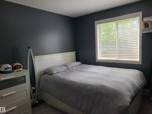 Room featuring dark-painted walls and a large window with white blinds - 116 5005 165 Avenue, Edmonton, AB 