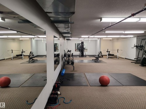 Fitness center with carpet flooring, extensive mirrored wall, and overhead fluorescent lighting - 116 5005 165 Avenue, Edmonton, AB 