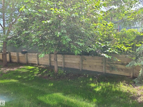 Manicured lawn with mature trees and a wood-finish retaining wall - 116 5005 165 Avenue, Edmonton, AB 