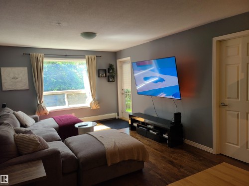 Living area with dark wood-finish flooring and neutral gray wall paint - 116 5005 165 Avenue, Edmonton, AB 