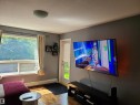 Living area featuring wood-finish flooring, a contemporary ceiling light fixture, and a large window with direct outdoor access - 116 5005 165 Avenue, Edmonton, AB 
