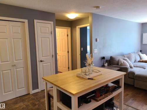 Kitchen island featuring a natural wood-finish countertop and open shelving - 116 5005 165 Avenue, Edmonton, AB 