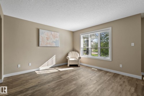 Spacious room featuring wood-finish flooring, neutral-toned walls, and white trim - 12809 203A, Edmonton, AB 