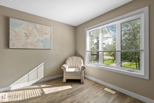 Expansive triple-pane window with white blinds, wood-finish flooring, neutral wall tones, white baseboards, and a textured ceiling - 12809 203A, Edmonton, AB 