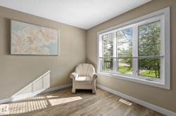 Expansive triple-pane window with white blinds, wood-finish flooring, neutral wall tones, white baseboards, and a textured ceiling - 