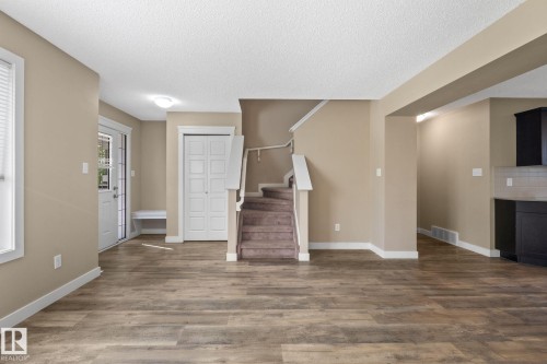Spacious open-concept living area featuring wood-finish flooring, neutral wall tones, and white trim throughout - 12809 203A, Edmonton, AB 