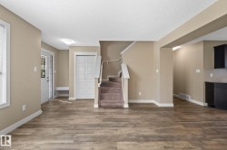 Spacious open-concept living area featuring wood-finish flooring, neutral wall tones, and white trim throughout - 