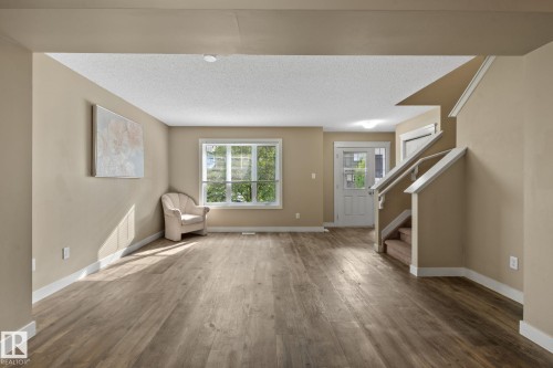 Spacious living area featuring wood-finish flooring, neutral wall tones, and white trim - 12809 203A, Edmonton, AB 