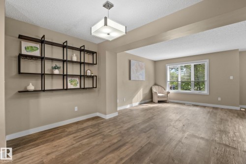 Spacious room featuring wood-finish flooring, a contemporary ceiling light fixture, and a built-in wall shelf - 12809 203A, Edmonton, AB 