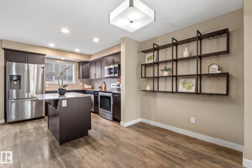 Open-concept kitchen and dining area featuring wood-finish flooring, recessed lighting, and a square ceiling fixture - 12809 203A, Edmonton, AB 