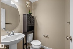 Pedestal sink with chrome faucet, oval wall mirror, and overhead vanity lighting - 