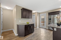 Kitchen featuring wood-finish flooring, dark wood cabinetry, light countertops, and a full-light exterior door - 