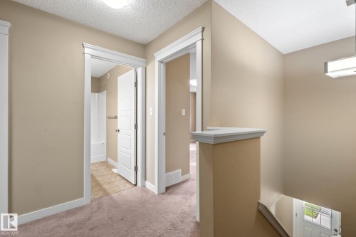 Upper-level landing featuring neutral-toned walls, white trim, and a textured ceiling - 12809 203A, Edmonton, AB 