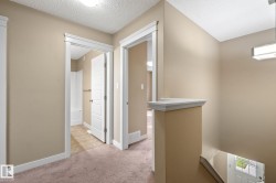 Upper-level landing featuring neutral-toned walls, white trim, and a textured ceiling - 