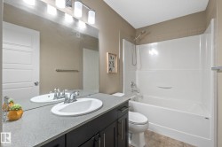 Bathroom featuring a dark wood-finish vanity with a light speckled countertop, an integrated oval sink, and a chrome faucet - 