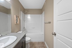 Contemporary bathroom featuring a white panel door, a dark wood-finish vanity with a light countertop, an undermount sink, a white toilet, and a white shower/tub combination with chrome fixtures - 