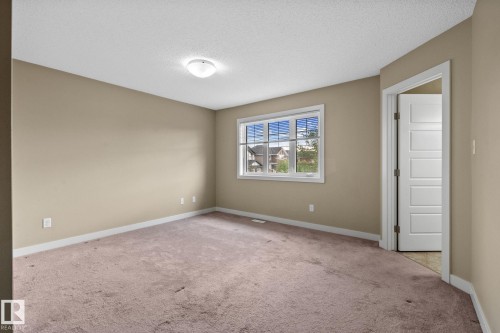 Neutral-toned room with a large window, light-colored carpeting, and a flush mount ceiling light fixture - 12809 203A, Edmonton, AB 