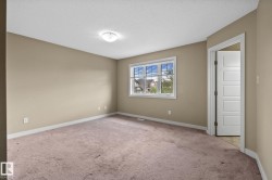 Neutral-toned room with a large window, light-colored carpeting, and a flush mount ceiling light fixture - 