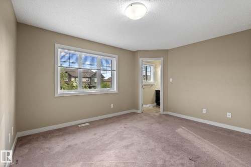 Carpeted room featuring neutral-toned walls, white baseboards, and a window with blinds - 12809 203A, Edmonton, AB 