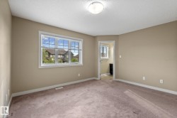 Carpeted room featuring neutral-toned walls, white baseboards, and a window with blinds - 