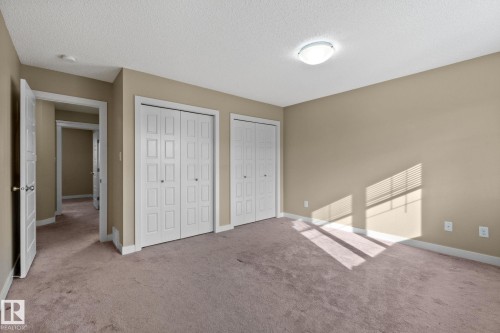 Spacious room featuring neutral-toned walls, plush carpeting, and two sets of white bi-fold closet doors - 12809 203A, Edmonton, AB 