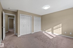 Spacious room featuring neutral-toned walls, plush carpeting, and two sets of white bi-fold closet doors - 