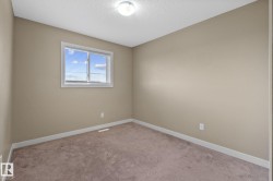 Neutral-toned room featuring a single window with blinds, light tan walls, and brown carpet flooring - 