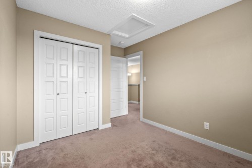 Bedroom featuring neutral tone carpeting, painted walls, white trim, and a bi-fold closet with panel detailing - 12809 203A, Edmonton, AB 