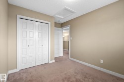 Bedroom featuring neutral tone carpeting, painted walls, white trim, and a bi-fold closet with panel detailing - 