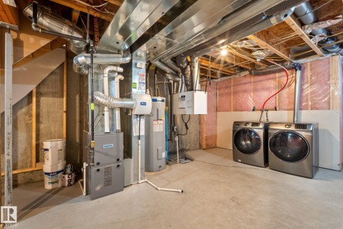 Utility area featuring exposed overhead ductwork, concrete flooring, furnace, and water heater - 12809 203A, Edmonton, AB 