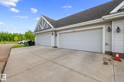 Two-car garage with white paneled doors, light grey siding, dark grey roof shingles, a decorative gable, and exterior wall sconces - 