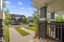 Exterior porch with stone-clad pillars, a dark gray railing, and a composite wood deck - 
