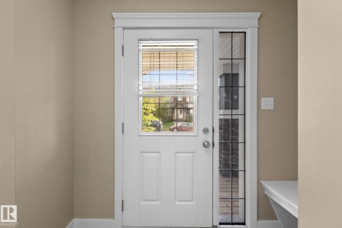 White paneled door with integrated window blinds, featuring a polished chrome doorknob and deadbolt - 12809 203A, Edmonton, AB 