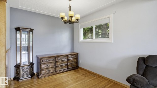 Room featuring light wood-finish flooring, a white-framed window, and a ceiling-mounted chandelier - 13008 105 Street Nw, Edmonton, AB 