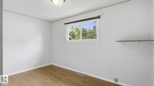 Room featuring wood-finish flooring, a white window frame, and a built-in shelving unit - 13008 105 Street Nw, Edmonton, AB 