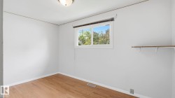 Room featuring wood-finish flooring, a white window frame, and a built-in shelving unit - 