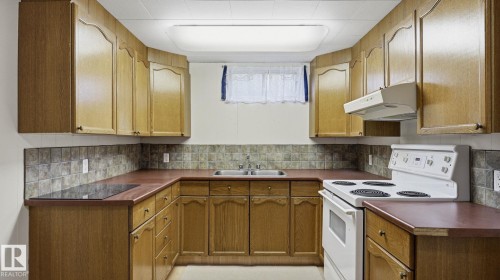 U-shaped kitchen featuring wood cabinetry, laminate countertops, a tile backsplash, and a double basin sink - 13008 105 Street Nw, Edmonton, AB 