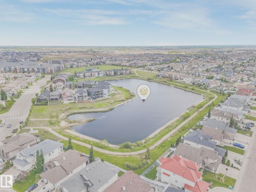 Aerial perspective showcasing a residential area with a prominent body of water and surrounding green spaces - 117 6070 Schonsee Way, Edmonton, AB 