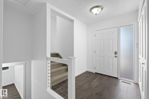 Entry foyer featuring dark wood-finish flooring, a white paneled entry door with frosted sidelight, and an overhead flush-mount light fixture - 2832 135 Avenue, Edmonton, AB - Indoor Photo Showing Other Room