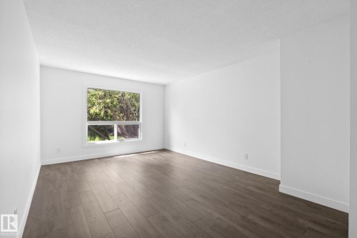 Spacious room featuring wood-finish flooring, white walls, and a large window with white trim - 2832 135 Avenue, Edmonton, AB - Indoor Photo Showing Living Room