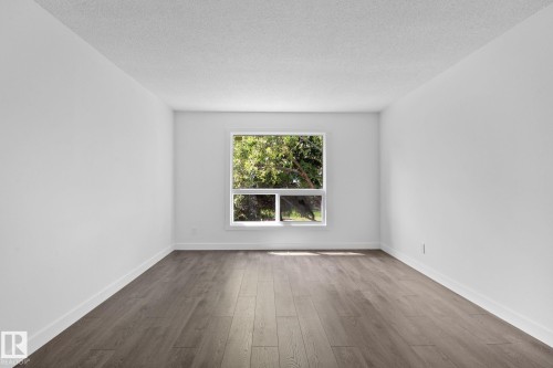 Spacious room with wood-finish flooring, crisp white walls, and a large window with white trim - 2832 135 Avenue, Edmonton, AB - Indoor
